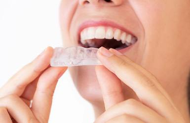 Woman holding a nightguard near her mouth