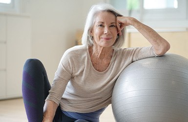 Senior woman smiling while resting against balance ball