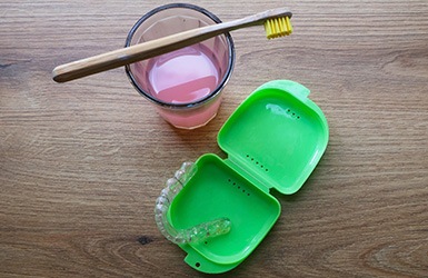 A nightguard and its case next to a toothbrush