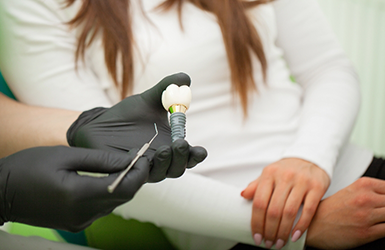 Dentist showing a model of a dental implant to a patient
