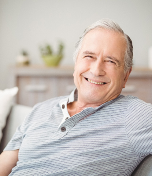 Older man on couch wearing his dentures 