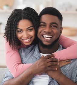 Smiling man and woman embracing against a yellow background