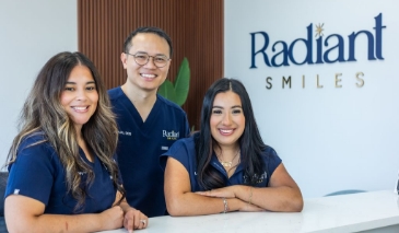 Woman swiping her payment card at front desk of dental office