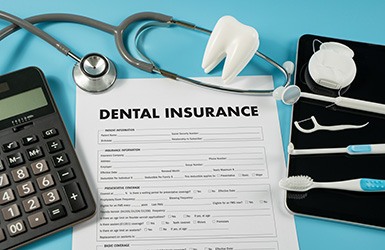 Dental insurance paperwork and calculator with various instruments 
