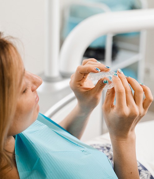 Patient holding clear aligner in treatment chair