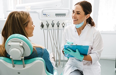 Dentist smiling while taking notes on clipboard