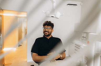 Patient with black glasses smiling in treatment chair