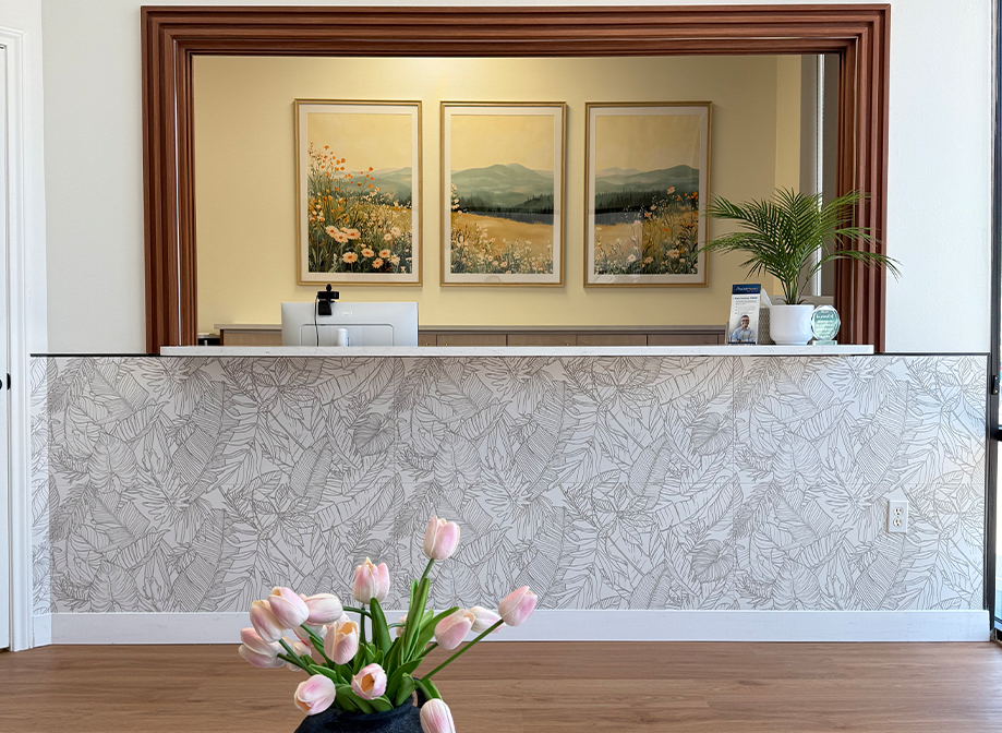 Front desk with paintings of mountains and valleys on the wall behind it