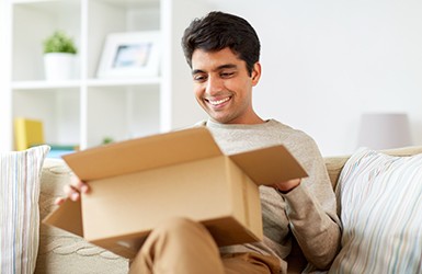 Man in beige clothes on couch opening box
