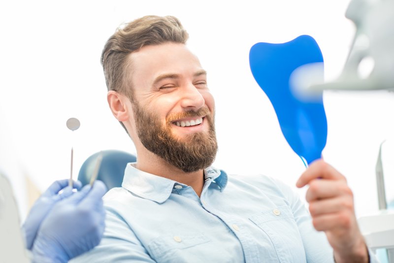Patient smiling in mirror at new veneers